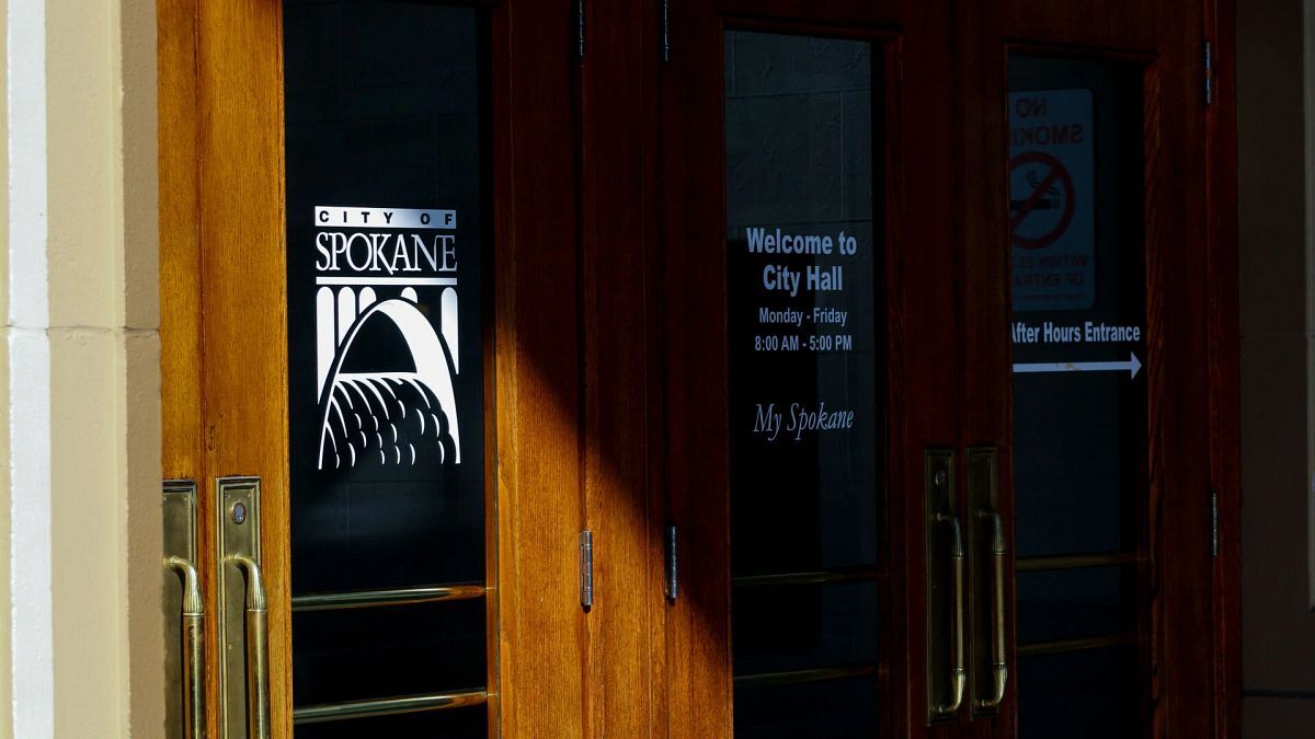 Entrance doors to Spokane City Hall with posted hours of operation